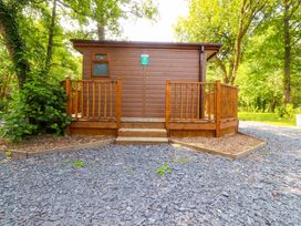 A cabin with a deck surrounded by trees at Shepherds Hut 2