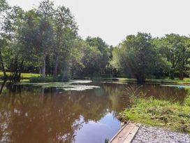 A pond surrounded by trees and grass at Shepherds Hut 2