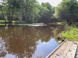 A pond surrounded by trees and grass at Shepherds Hut 2 