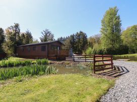 A cabin with a deck near a pond at Butterfly Hut 2 Forton near Garstang