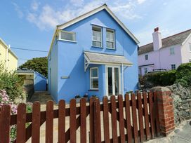 A house with a blue exterior and a wooden fence at Trwst Y Don in Rhosneigr
