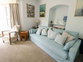 A living room with a sofa, chair, and coffee table at Trwst Y Don Rhosneigr