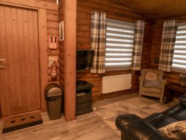A living room with a television and an armchair at Farnes Lodge in Longframlington