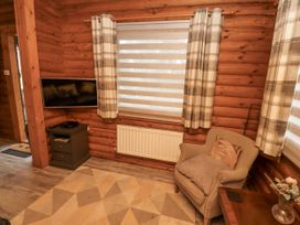 A living room with a television and an armchair at Farnes Lodge in Longframlington