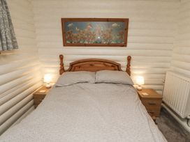 A bedroom with a bed, nightstand, lamp, and radiator at Farnes Lodge in Longframlington