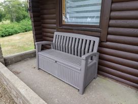 A bench in front of a log cabin at Farnes Lodge Longframlington