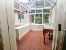 A conservatory with a table and windows at The Anchorage in Hoveton & Wroxham