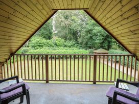 A balcony with chairs and table overlooking a garden at The Anchorage in Hoveton & Wroxham