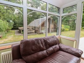 A conservatory with a sofa and windows overlooking the garden at The Anchorage in Hoveton & Wroxham