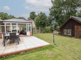 A garden with a patio and a conservatory at The Anchorage in Hoveton & Wroxham