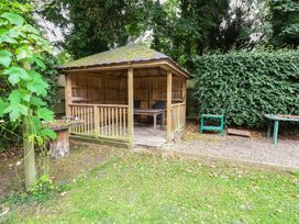 A wooden gazebo with a table and chair in a garden at The Anchorage Hoveton & Wroxham