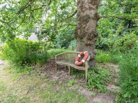 A bench with a lifebuoy next to a tree in a garden at The Anchorage in Hoveton & Wroxham