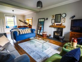 A living room with a blue sofa and piano at Grove House in Grange-Over-Sands