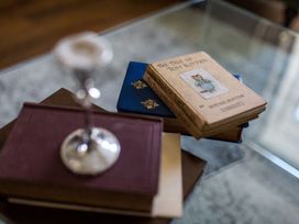 A collection of books and a glass on a table at Grove House in Grange-Over-Sands