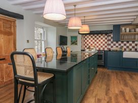 A kitchen with an island and stools at Grove House in Grange-Over-Sands