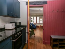 A kitchen with various appliances and an opening to a living area at Grove House in Grange-Over-Sands