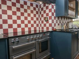 A kitchen with a stove, oven, and checkered wall tiles at Grove House in Grange-Over-Sands