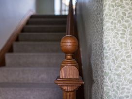 A staircase with wooden railing and patterned wallpaper at Grove House in Grange-Over-Sands