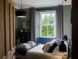 A bedroom with a bed, dresser, and window at Grove House in Grange-Over-Sands
