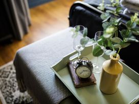 A tray with a clock, glasses, book and vase in a living room at Grove House in Grange-Over-Sands