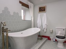 A bathroom featuring a bathtub, toilet, towels, and a mirror at Grove House in Grange-Over-Sands