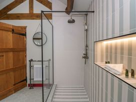 A bathroom with a shower and towels on a shelf at Grove House in Grange-Over-Sands