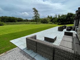 A patio with outdoor furniture and a grassy area at Grove House in Grange-Over-Sands