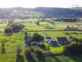 A house and barn in a field with trees at Grove House in Grange-Over-Sands