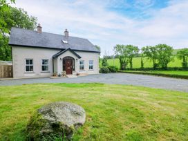 A house with a front door and windows surrounded by grass and trees at The Lodge in Gorey, County Wexford
