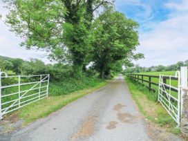 A dirt road with trees and a white gate at The Lodge in Gorey, County Wexford