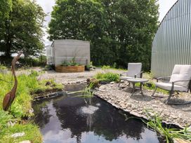 An outdoor area with a pond, chairs and a shed at Gwybedog in Llanwrda