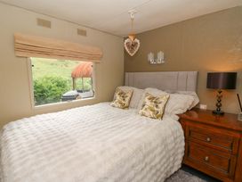 A bedroom with a bed, pillows, and a window at Gwybedog in Llanwrda