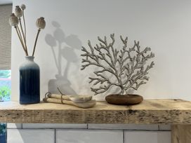 A decorative arrangement including a vase with flowers and a coral piece on a wooden shelf at 21 Station Hill