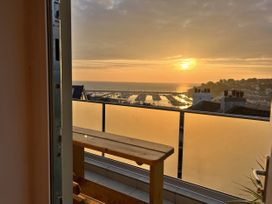 A balcony with a wooden bench overlooking a marina at Still Waters in Brixham