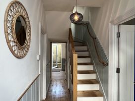 A hallway with a staircase and a mirror at Still Waters in Brixham