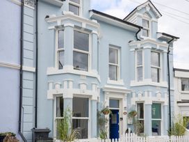A house with multiple windows and a blue door at Still Waters in Brixham