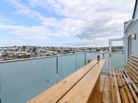 A balcony with a wooden table and chairs overlooking Brixham