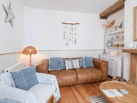 A living room with a sofa and shelves at Still Waters in Brixham