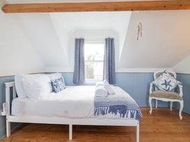 A bedroom with a bed and chair at Still Waters in Brixham