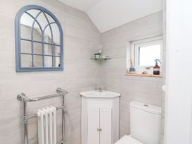 A bathroom with a mirror, hand basin, toilet and window at Still Waters in Brixham