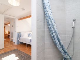 A bathroom with a shower curtain and wooden floor at Still Waters in Brixham