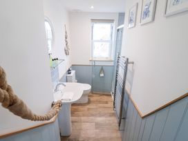 A bathroom with a sink, toilet, and window at Still Waters in Brixham