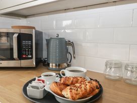 A kitchen counter with a kettle, microwave, coffee and pastries at Penny Farthing Inn Aston Crews near Ross-On-Wye