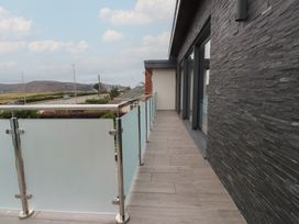 A balcony with a glass railing and stone wall at 70 Deganwy Road in Deganwy