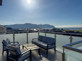 An outdoor balcony with seating and a table overlooking the sea and mountains at 70 Deganwy Road, Deganwy