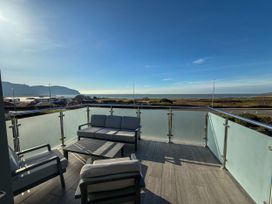 A balcony with seating and a table overlooking the ocean at 70 Deganwy Road in Deganwy