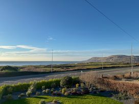 View of the ocean and mountains with a road in front at 70 Deganwy Road in Deganwy
