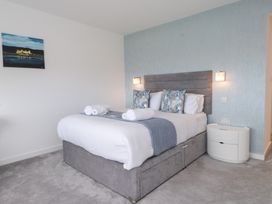 A bedroom with a bed, table, and painting at Môr Glas in Deganwy