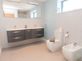 A bathroom with a sink, toilet, and mirror at Môr Glas, Deganwy
