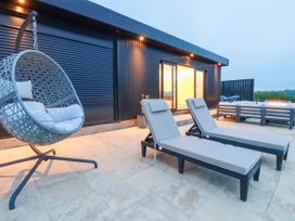An outdoor area with sun loungers and a hanging chair at The Lake Boat exclusive retreat Black Cross near St Columb Major